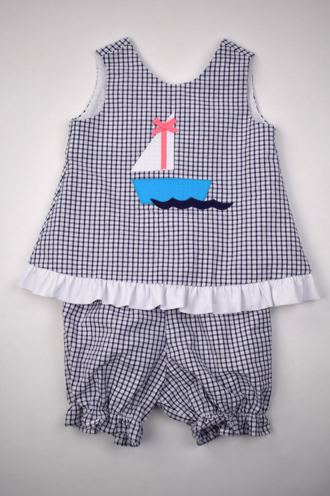 Sail away in style with our Sailboat Popover Set! Designed for toddler girls, this set features a charming navy and white gingham print with a playful sailboat applique. The ruffle hem adds a cute touch. Perfect for any summer adventure, this set will keep your little one cool and comfortable.