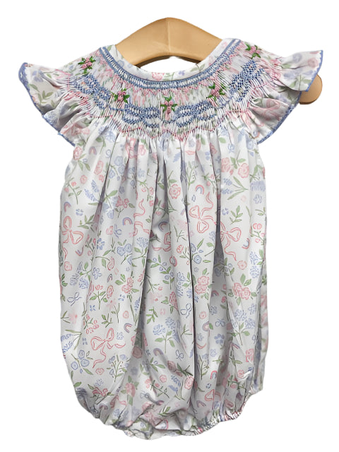 Introducing the Kate Bow Bishop Bubble from Shop Teeta - the perfect addition to your little one's wardrobe. This adorable bubble features a bishop smocked neckline and a charming floral and bow motif in pink, blue, and green. Let your infant girl stand out in style and comfort with this must-have piece.