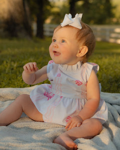 Dress your infant girl in the adorable Ada Ribbons &amp; Bows Bubble from The Yellow Lamb. This charming bubble style outfit features a pink bow and ribbon design and a back bow tie. Don't forget to grab the matching Ada Ribbons &amp; Bows Dress for a sibling set!